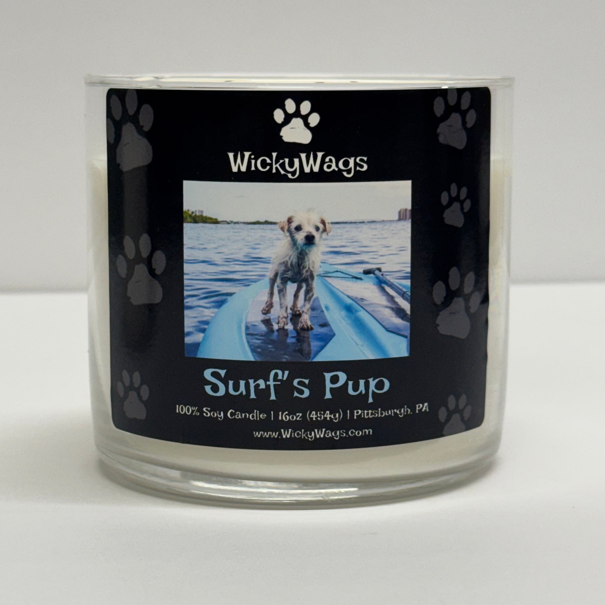 WickyWags candle labeled 'Surf's Pup' with a dog on a leash in water